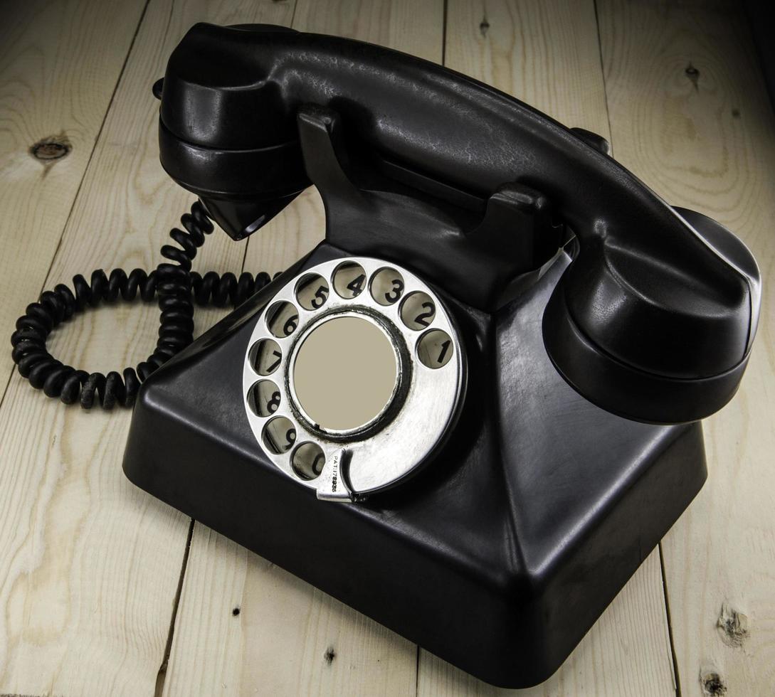 Old vintage phone with rotary disc on wooden table grunge background photo