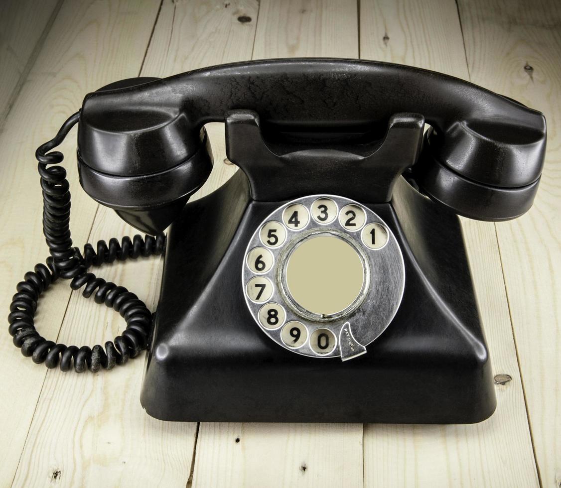 Old vintage phone with rotary disc on wooden table grunge background photo