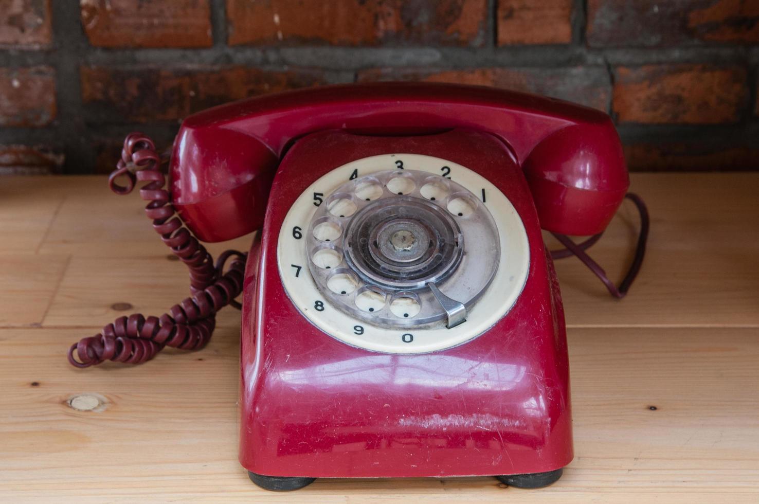 Viejo teléfono vintage rojo con fondo de mesa de madera foto