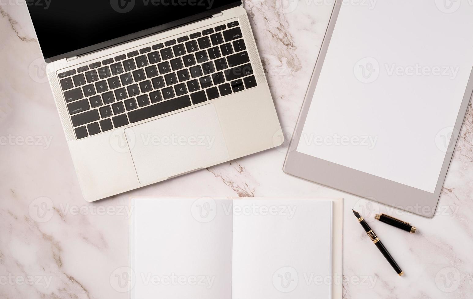 Top view desktop blank calendar, notebook and laptop on light gray marble background photo