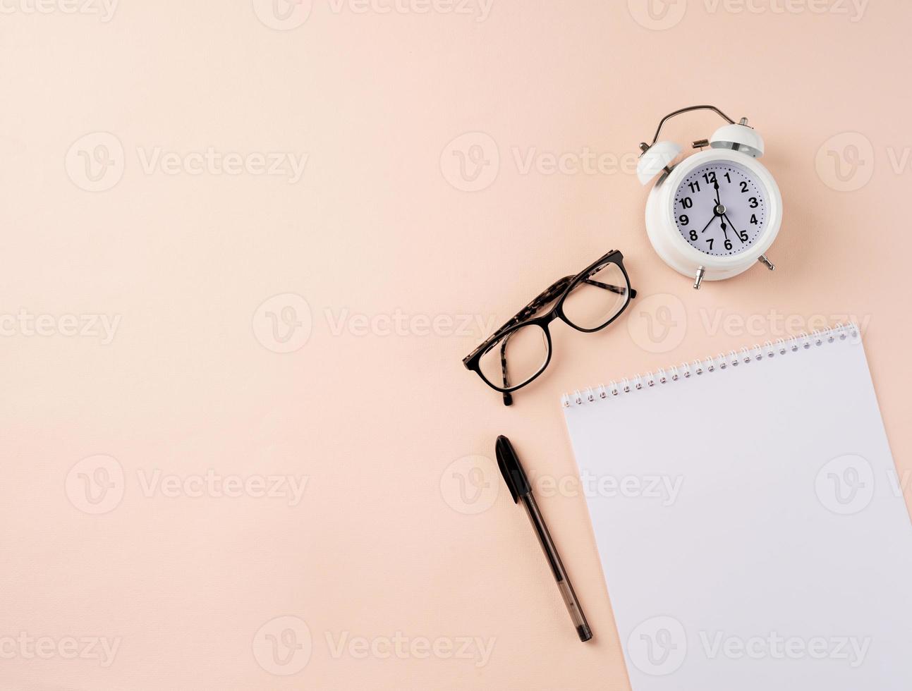 Top view blank calendar, glasses, clock and pen on beige background photo