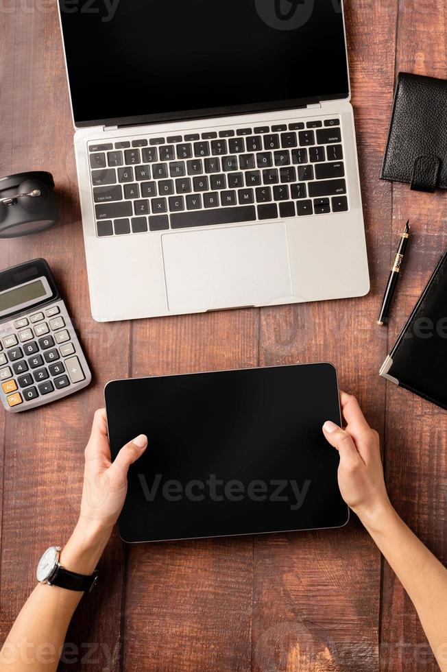 Top view desktop blank tablet, laptop and stationery on wooden background photo