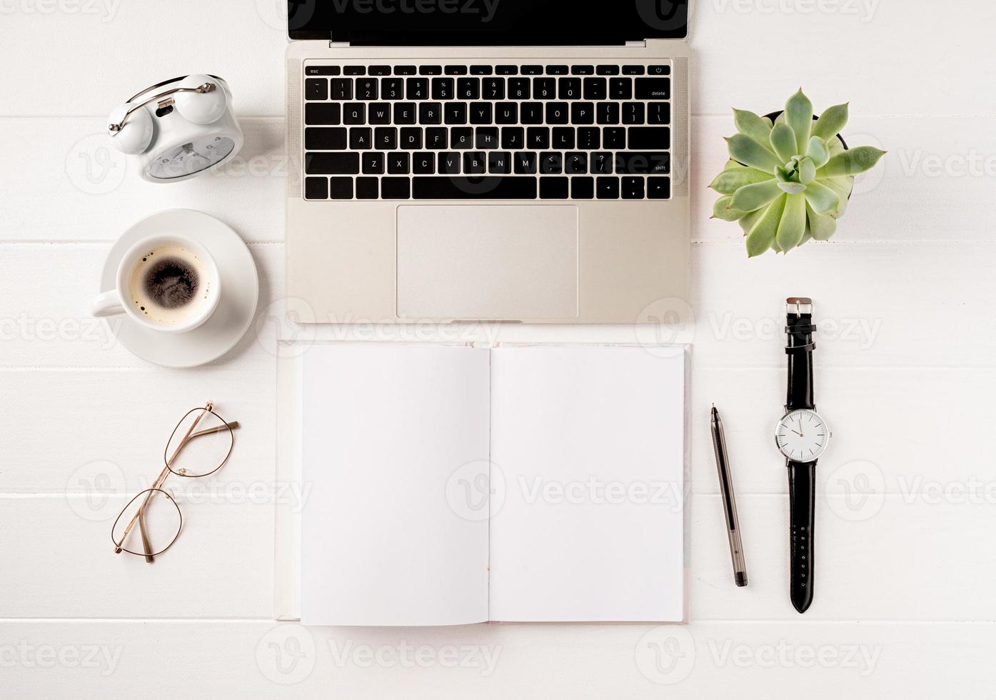 Vista superior de escritorio portátil, portátil y papelería en blanco sobre fondo blanco. foto