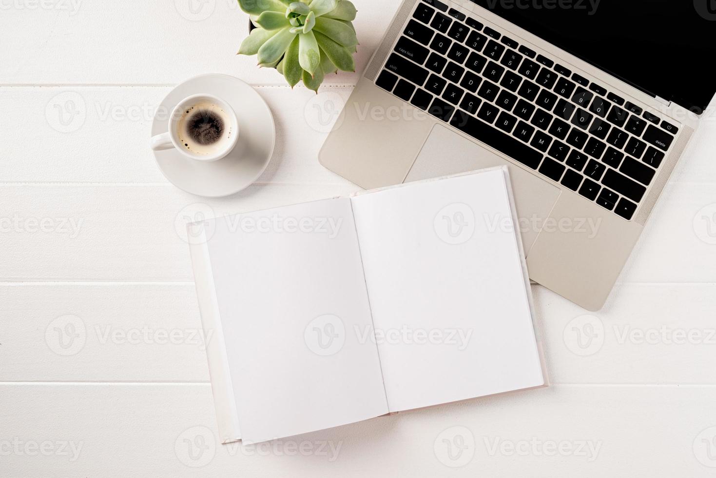 Vista superior de escritorio portátil, portátil y papelería en blanco sobre fondo blanco. foto