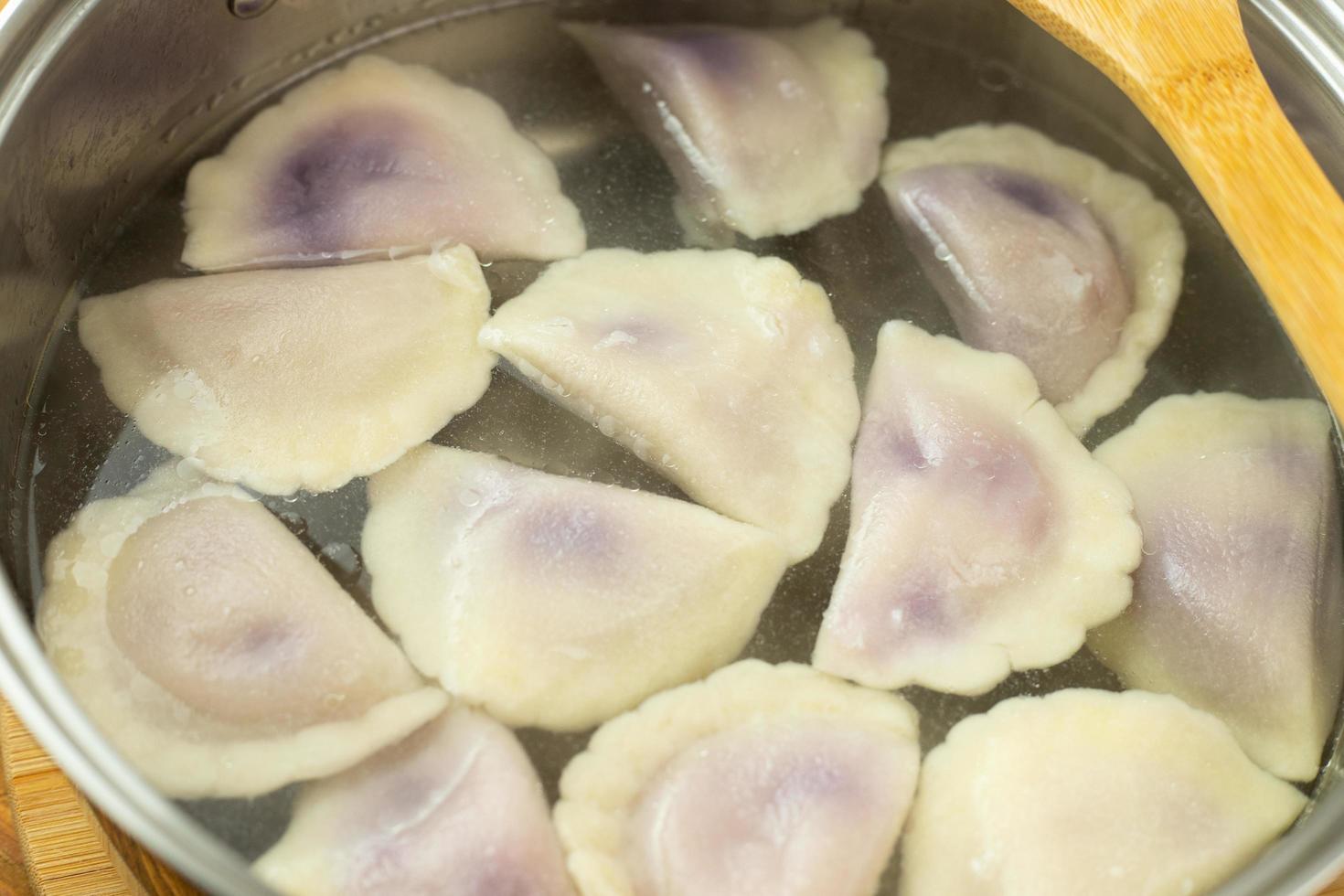 Dumplings with blueberries and cheese boiled in water in a pot. photo