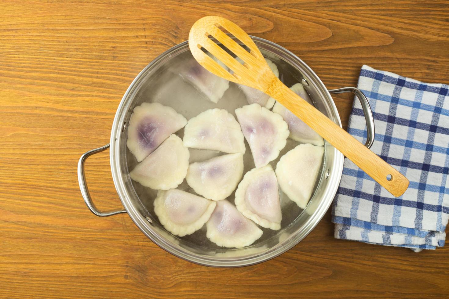 Dumplings with blueberries and cheese boiled in water in a pot. photo
