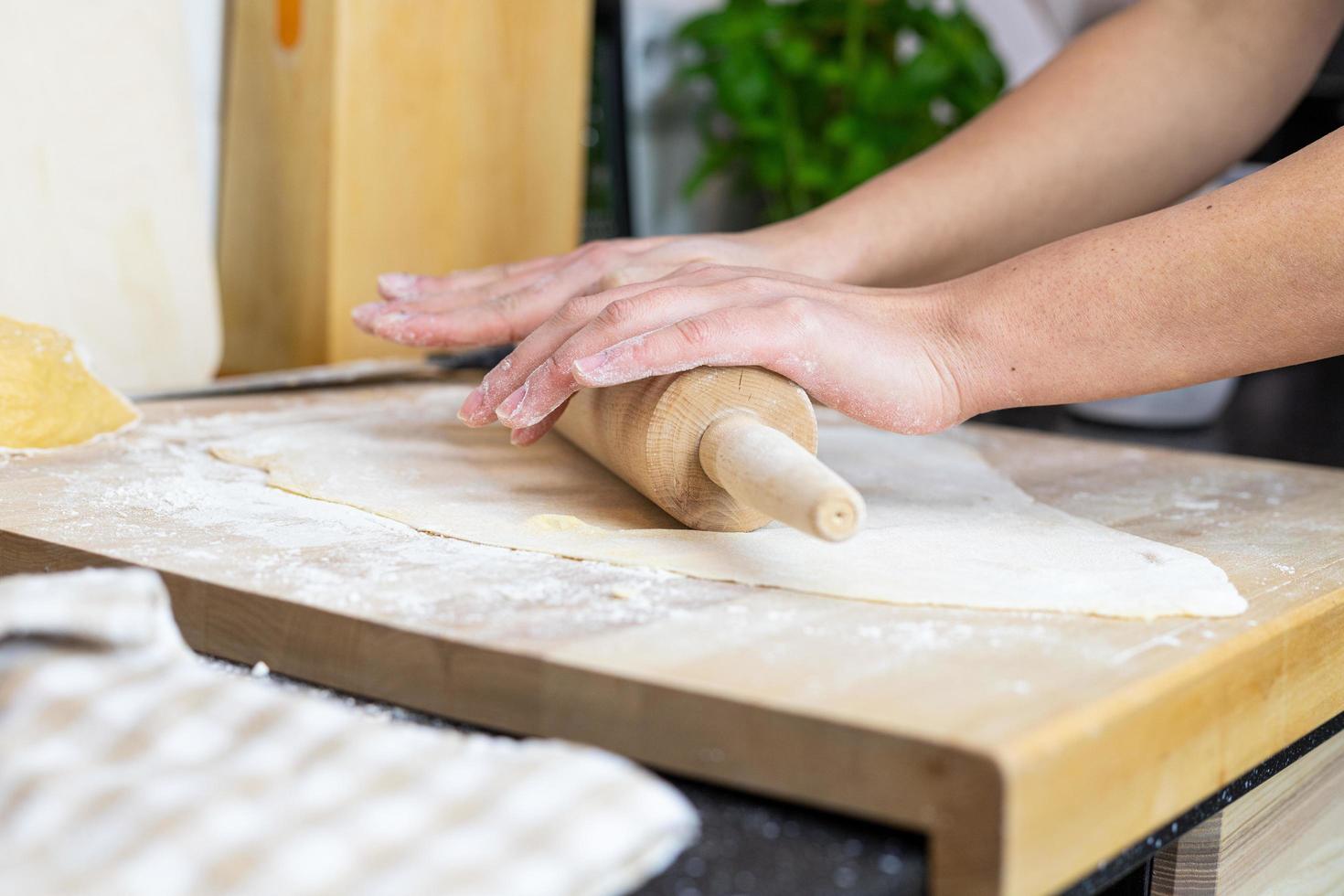 una persona enrollando la masa para hacer pasta de lasaña casera. foto