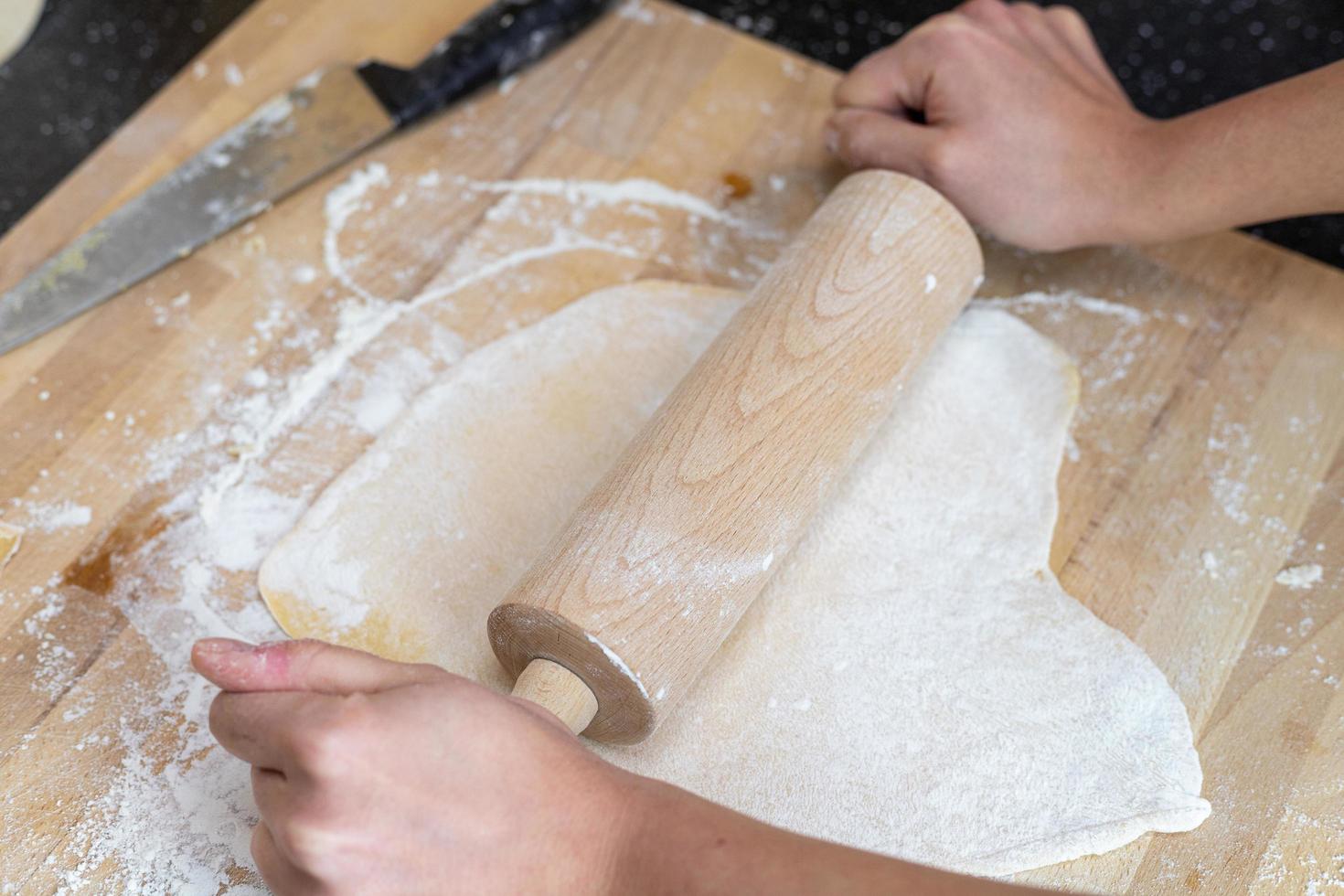 una persona enrollando la masa para hacer pasta de lasaña casera. foto