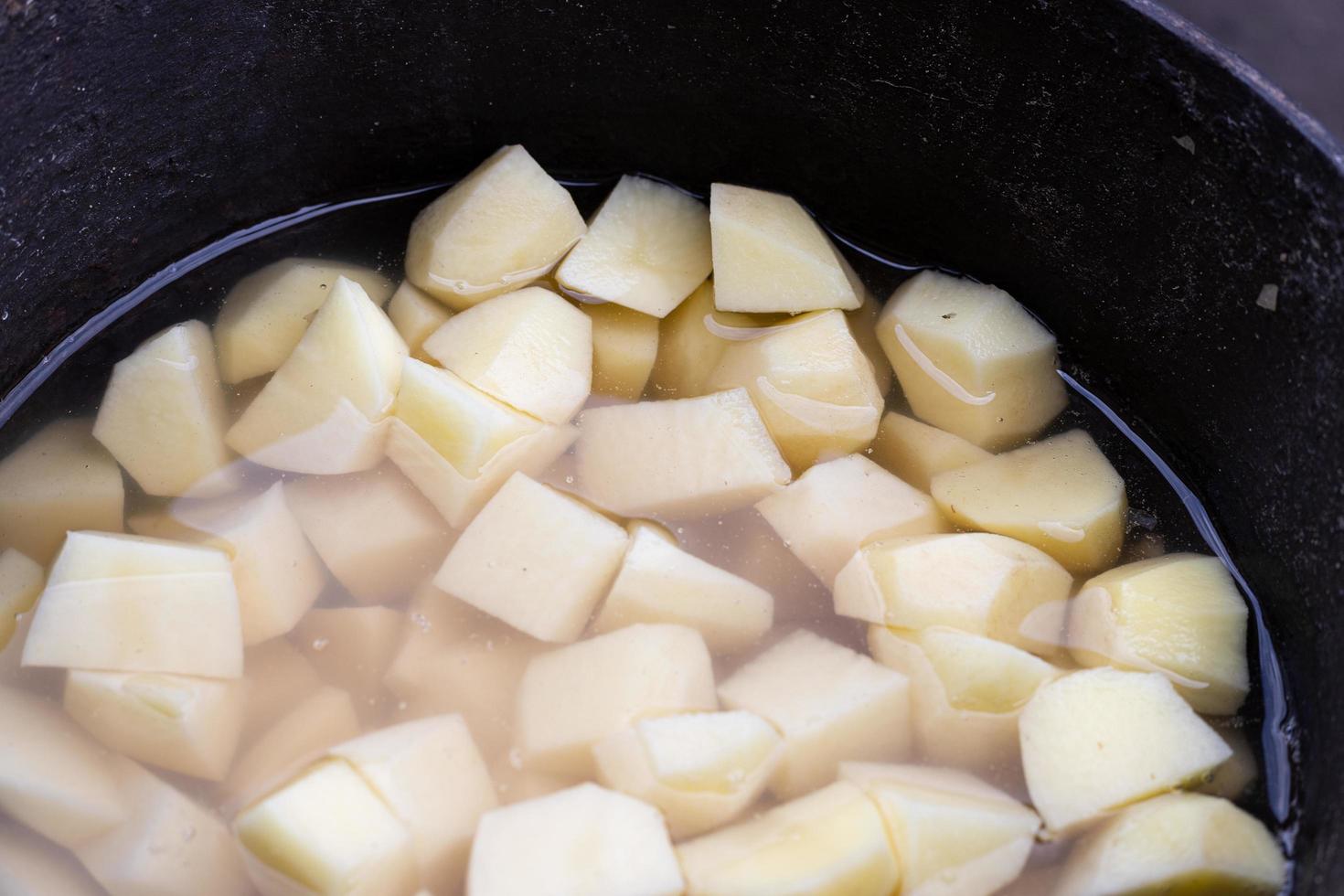 Peeled potatoes in a cast iron pot. Preparation of baked potatoes. Traditional Polish dish. photo