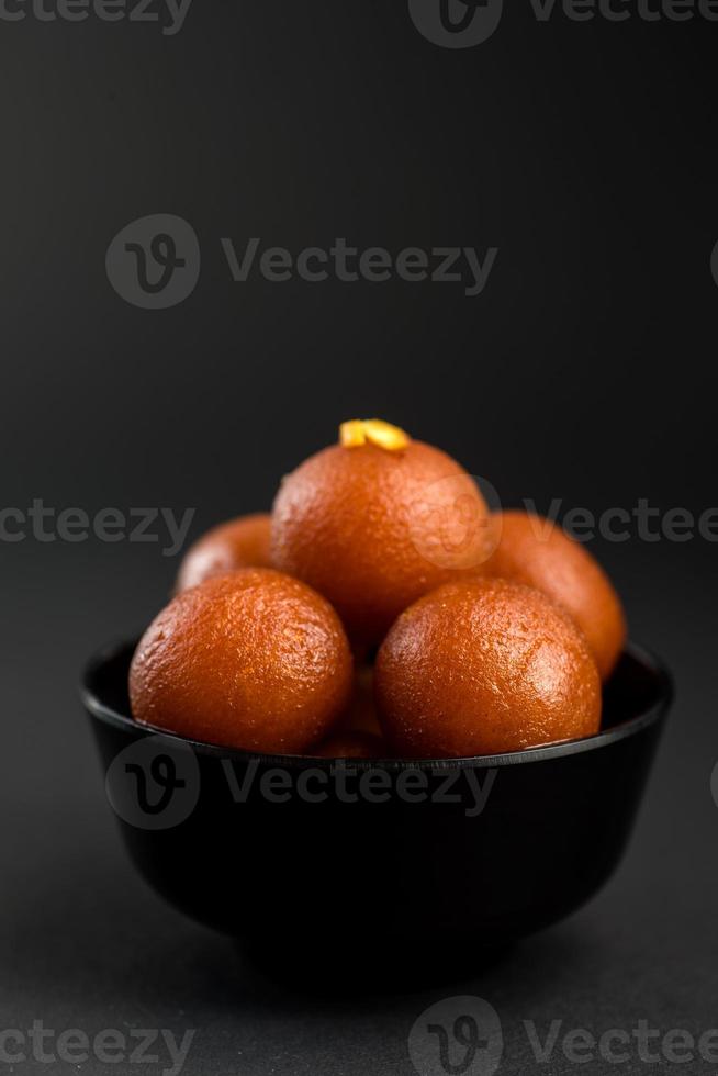 Gulab Jamun in bowl on black background. Indian Dessert or Sweet Dish. photo