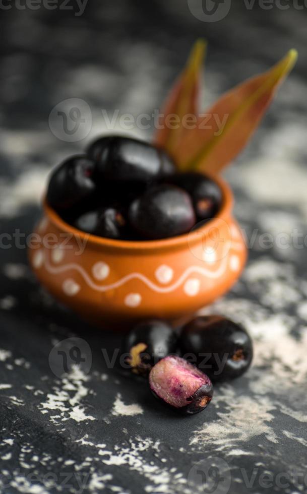 ciruela jambolan o fruta jambul o jamun, ciruela java syzygium cumini con hojas sobre fondo de textura de piedra. foto