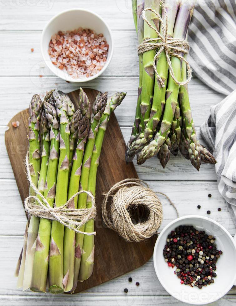 Bunch of raw asparagus stems with different spices photo
