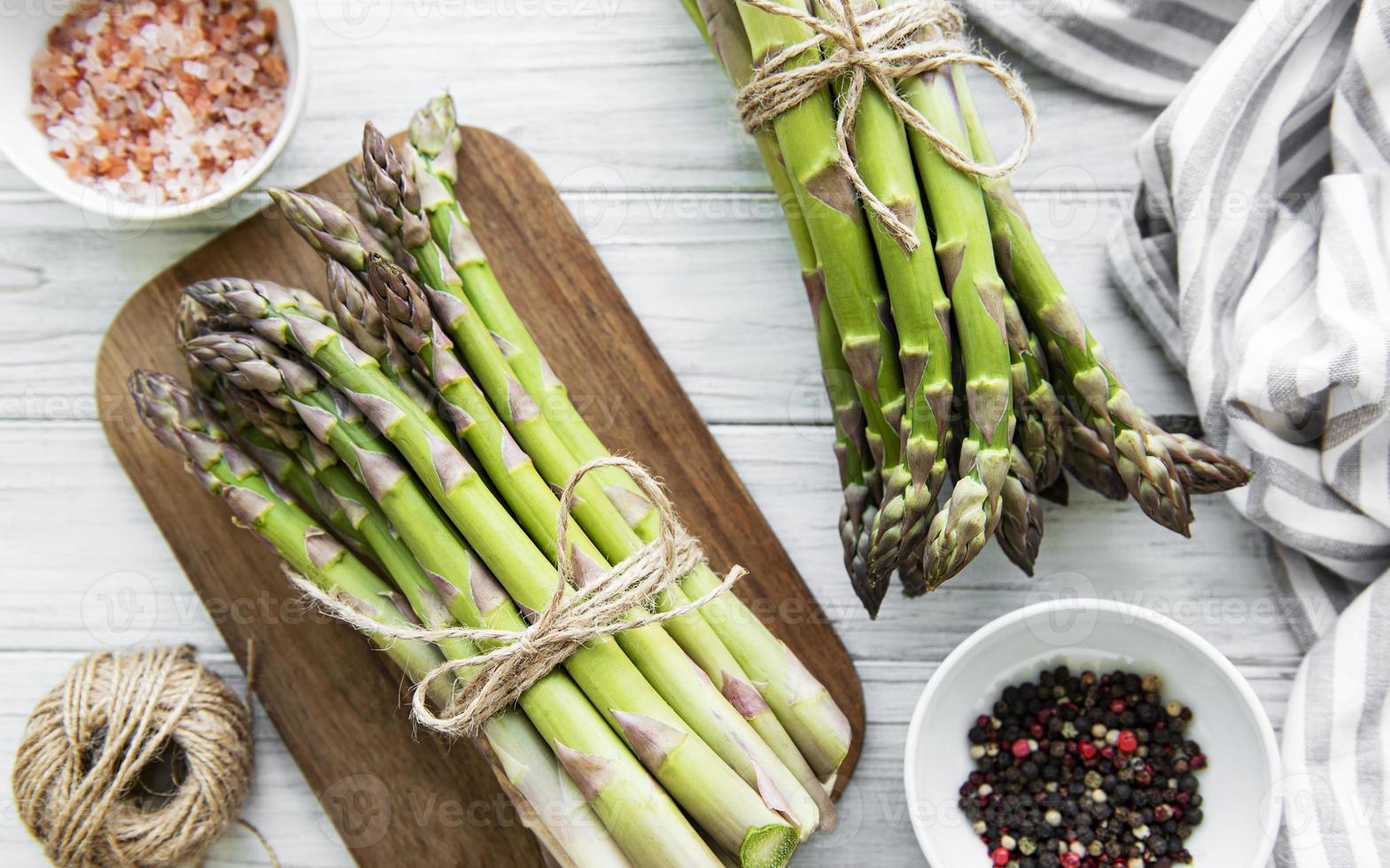 Bunch of raw asparagus stems with different spices photo