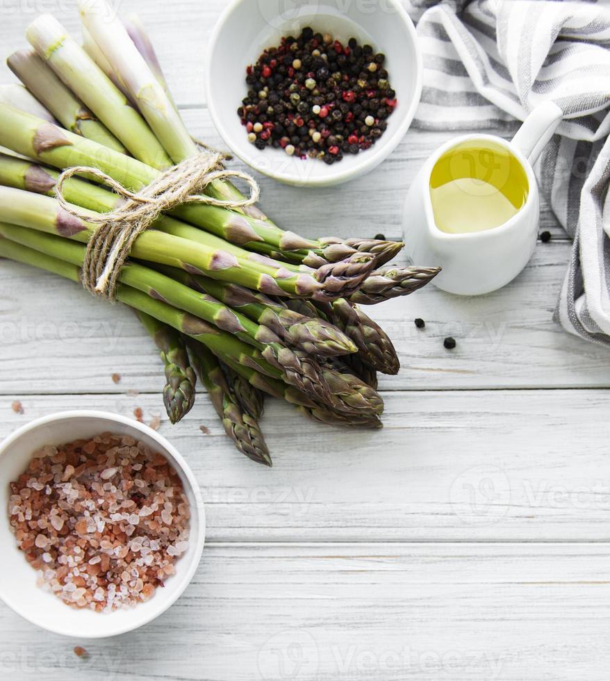 Bunch of raw asparagus stems with different spices photo