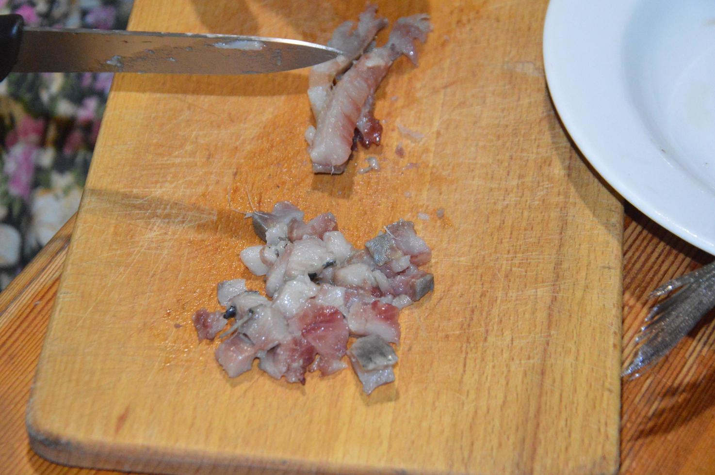 Slicing herring with a knife on a kitchen board photo