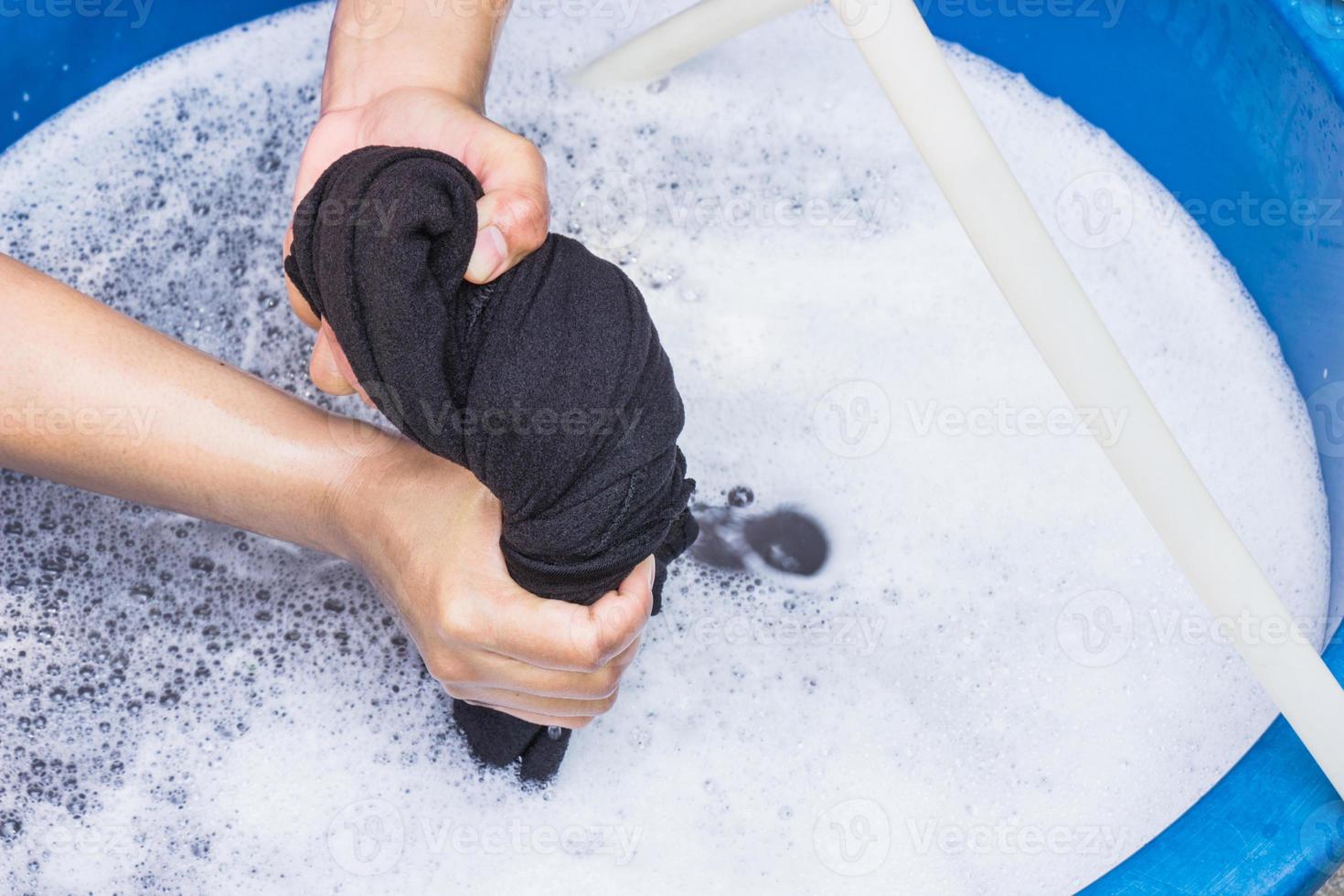 Las manos femeninas lavan la ropa a mano con detergente en una palangana. enfoque selectivo y espacio para texto. foto