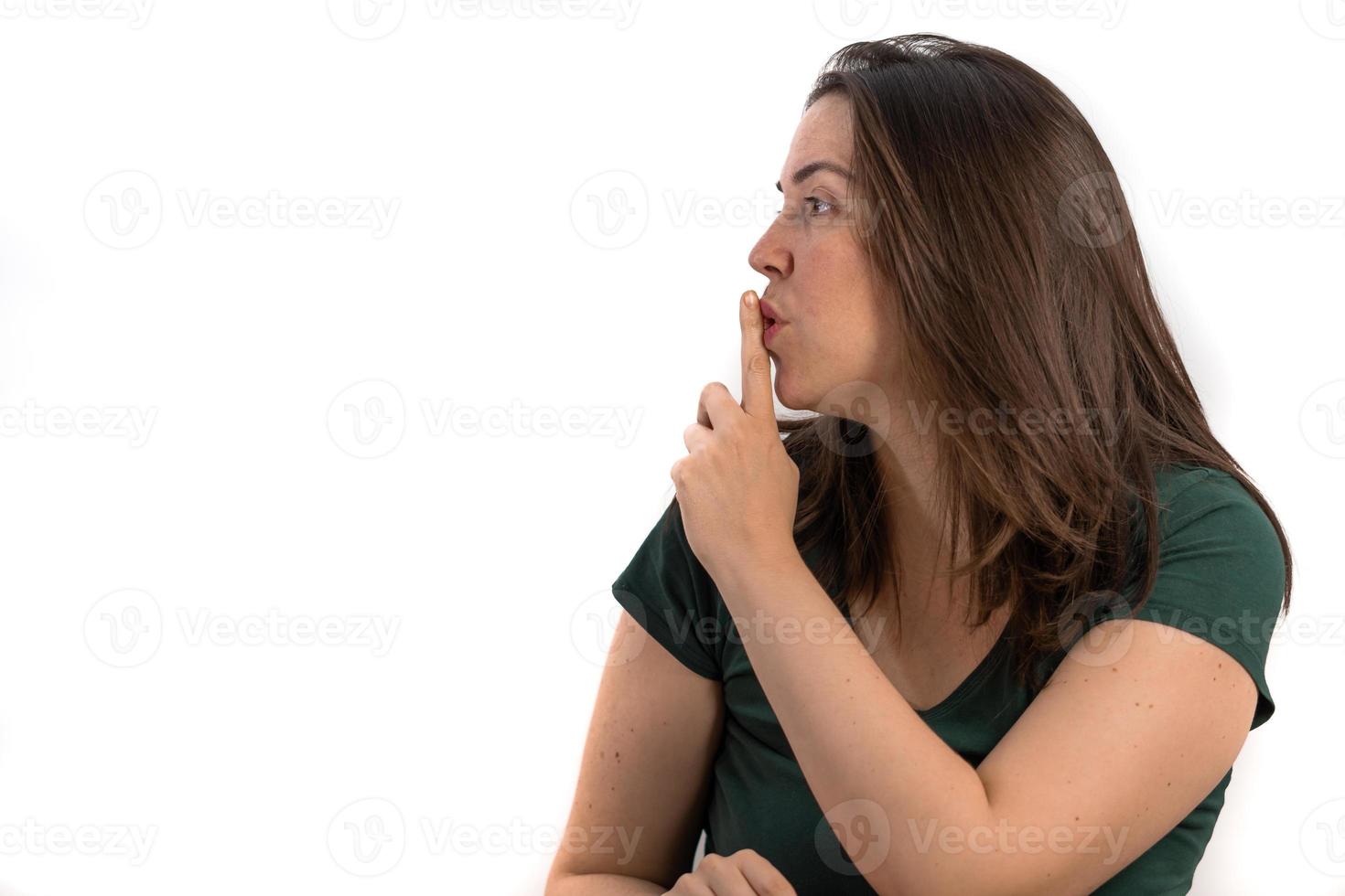 Chica morena de perfil pidiendo silencio con el dedo en los labios foto