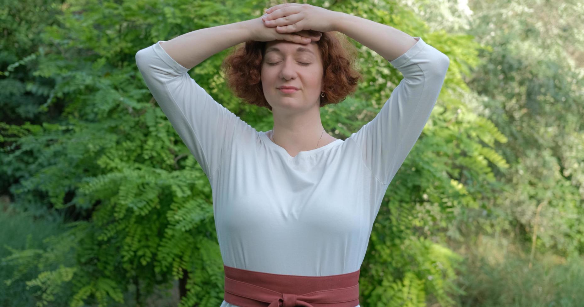 Female practicing qigong and meditation in summer park or forest photo