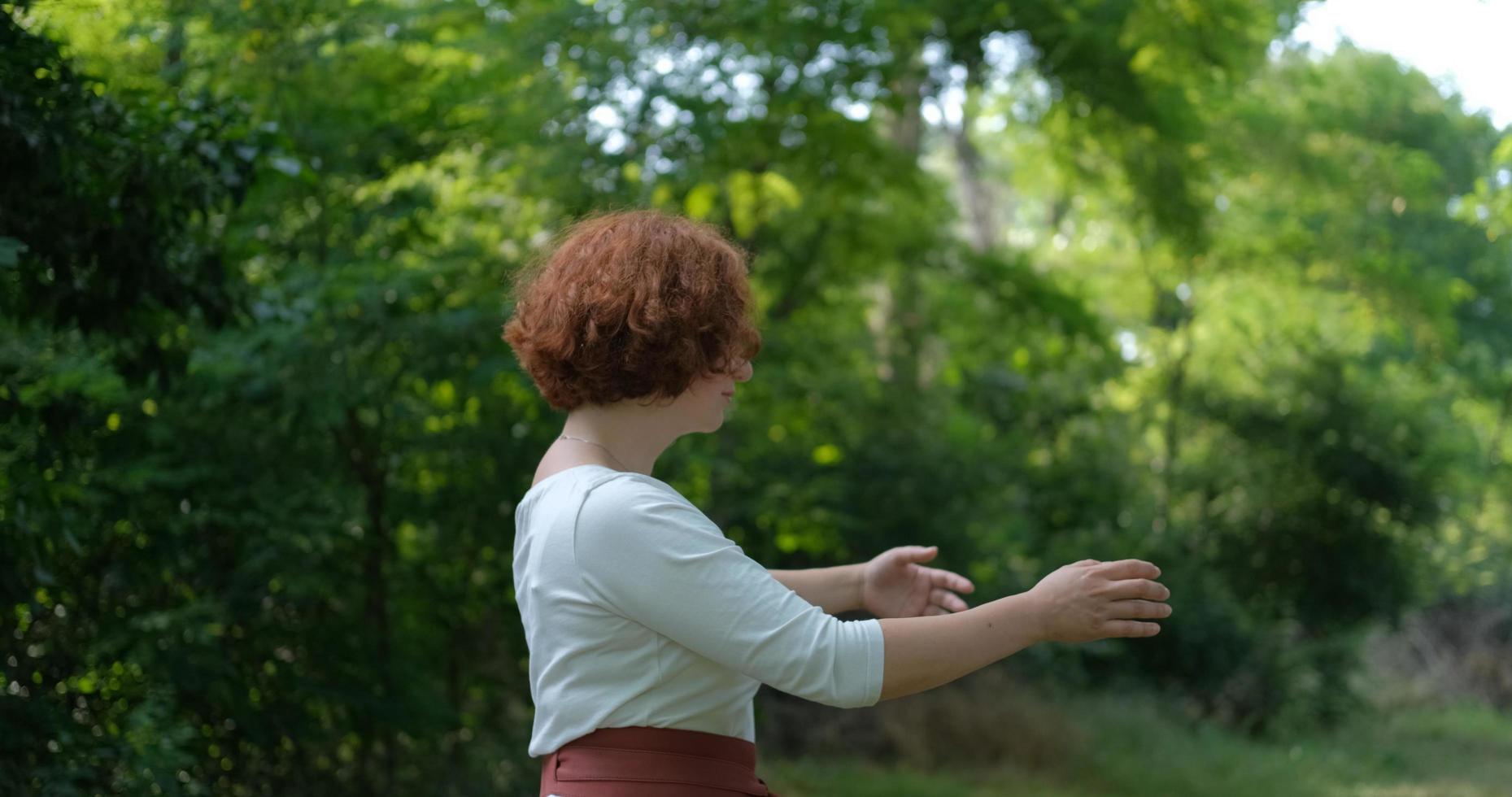 mujer practicando qigong y meditación en el parque o bosque de verano foto