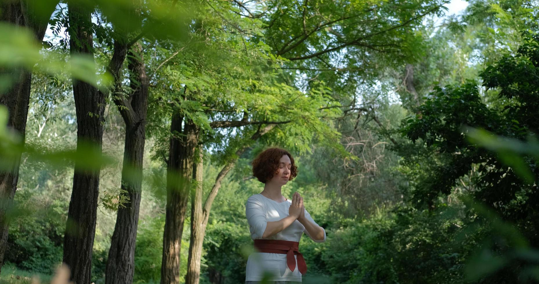 mujer practicando qigong y meditación en el parque o bosque de verano foto