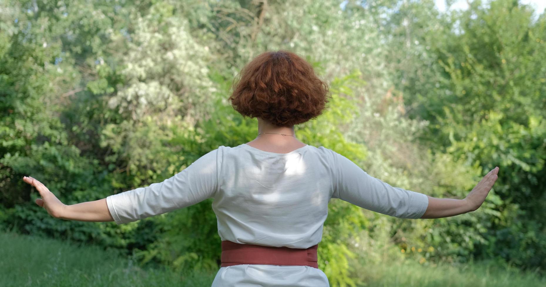 mujer practicando qigong y meditación en el parque o bosque de verano foto