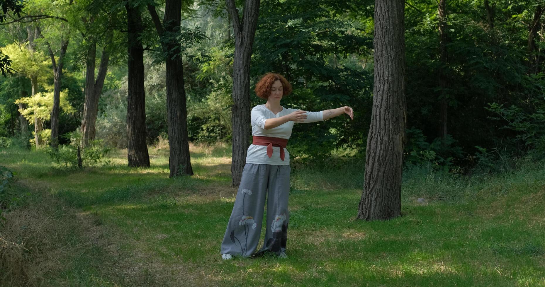 Female practicing qigong and meditation in summer park or forest photo