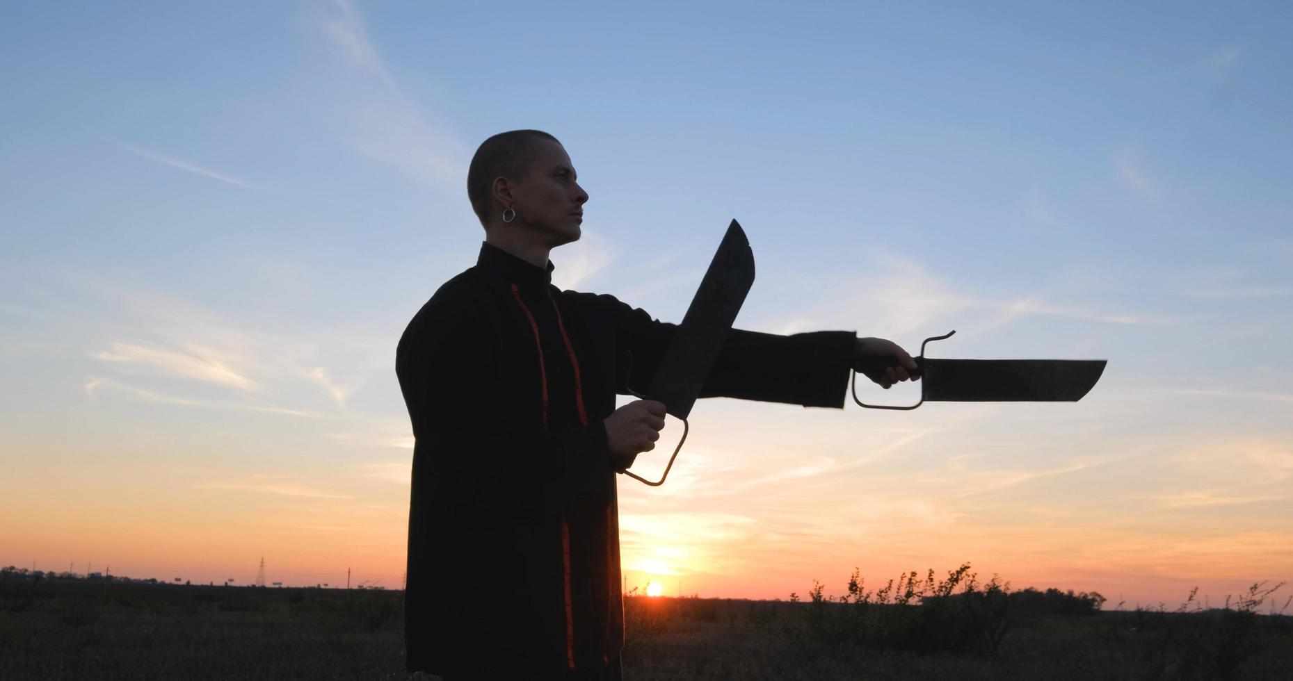 Silueta de joven luchador de kung fu practicando solo en los campos durante la puesta de sol foto