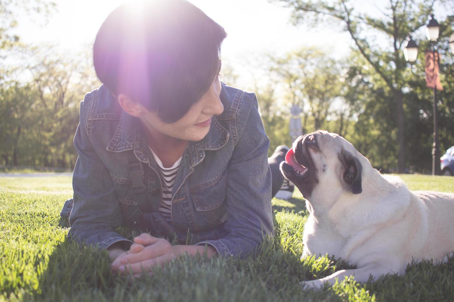 Retrato de mujer joven con perro pug en el parque foto