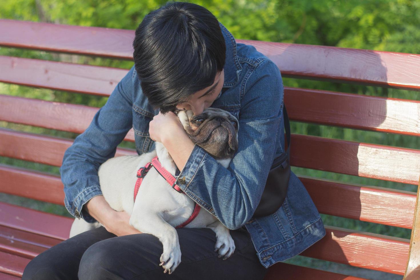 Retrato de mujer joven con perro pug en el parque foto