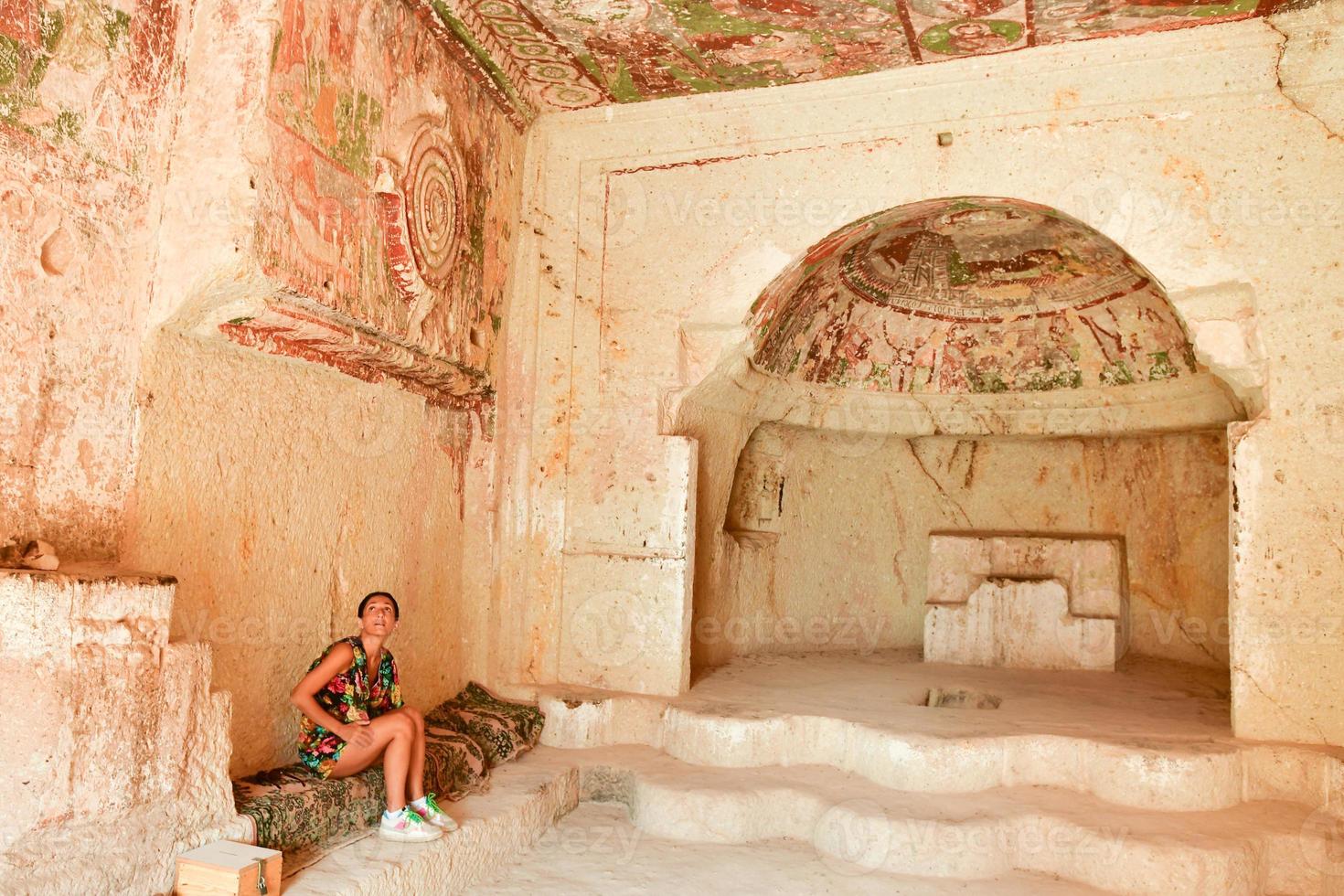 turista en pancarlik kilise iglesia edificio de cuevas de piedra caliza. vista interior escritos y pinturas antiguas sobre el sellado en capadocia. explorar gemas ocultas en concepto de Turquía foto