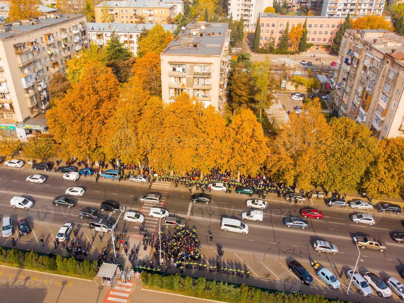 Aerial top down view Police officers surround crowd of aggressive protestors in street in public anti-government protest photo