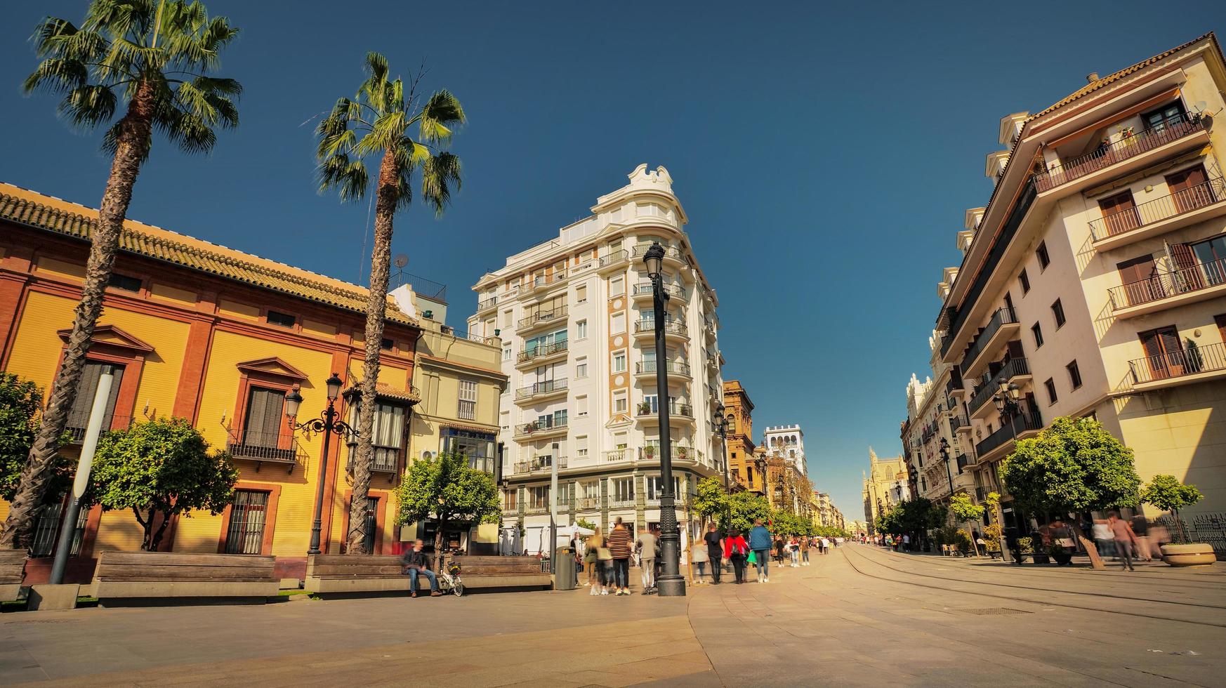 Seville, Spain - February 15th, 2020 - the busy Constitution Avenue with crowds of people walking along and trams in Seville City Center. photo