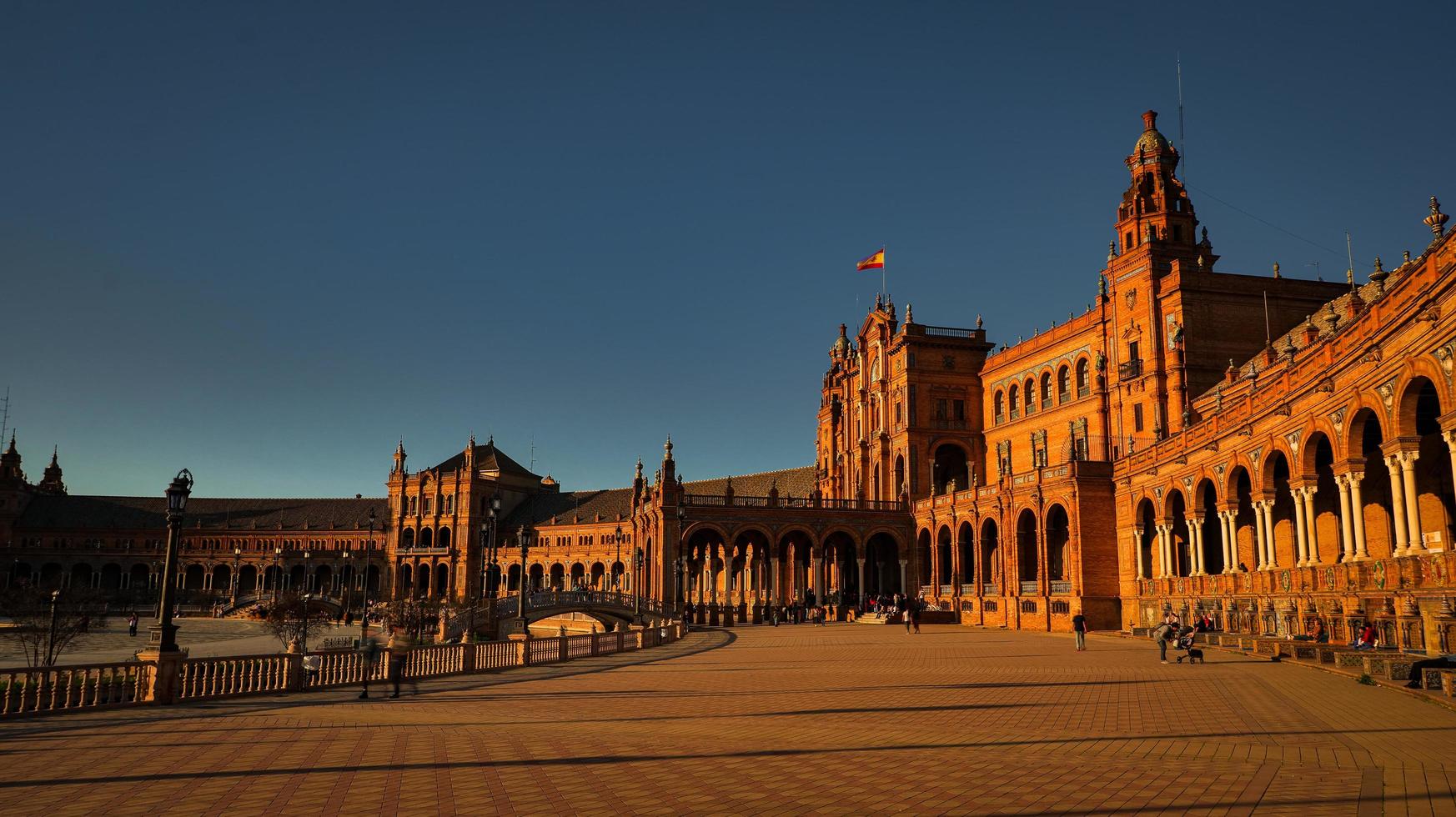 Seville, Spain - February 18th, 2020 - Tourists strolling in Plaza de Espana with beautiful Architecture Details at sunset in Seville City Center. photo