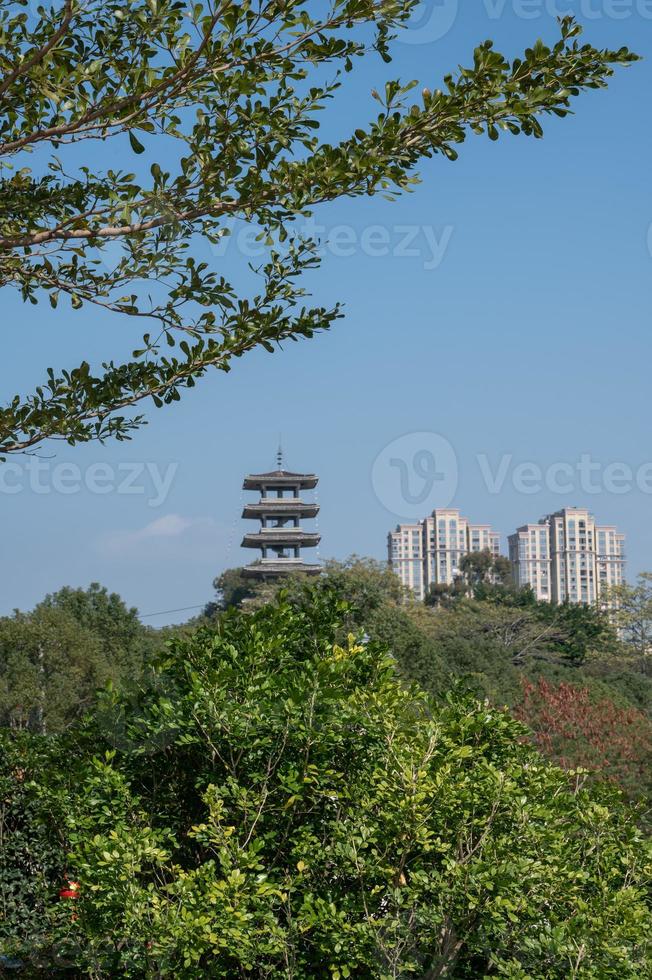 una torre bajo el cielo azul y árboles verdes. foto