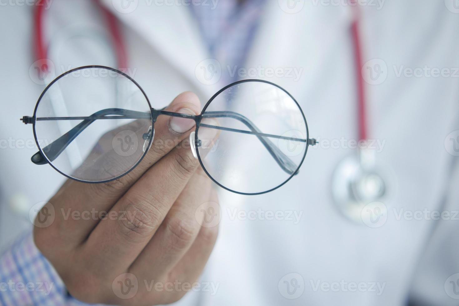 manos del doctor dando un par de anteojos negros al paciente. foto