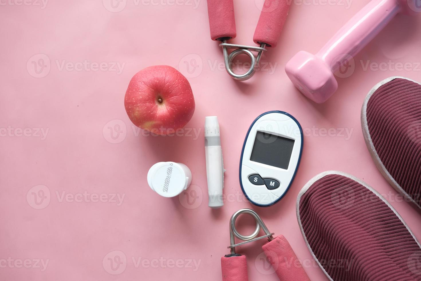 Herramientas de medición para diabéticos, zapato y manzana sobre fondo de color rosa foto