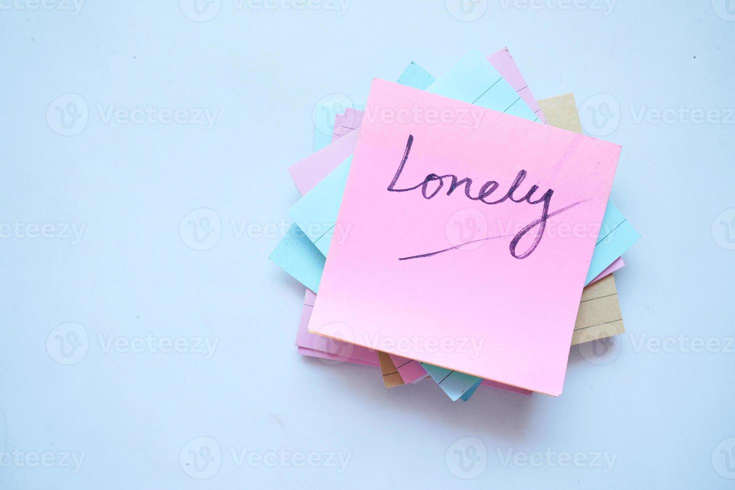 hand written lonely text on a sticky note on white background photo