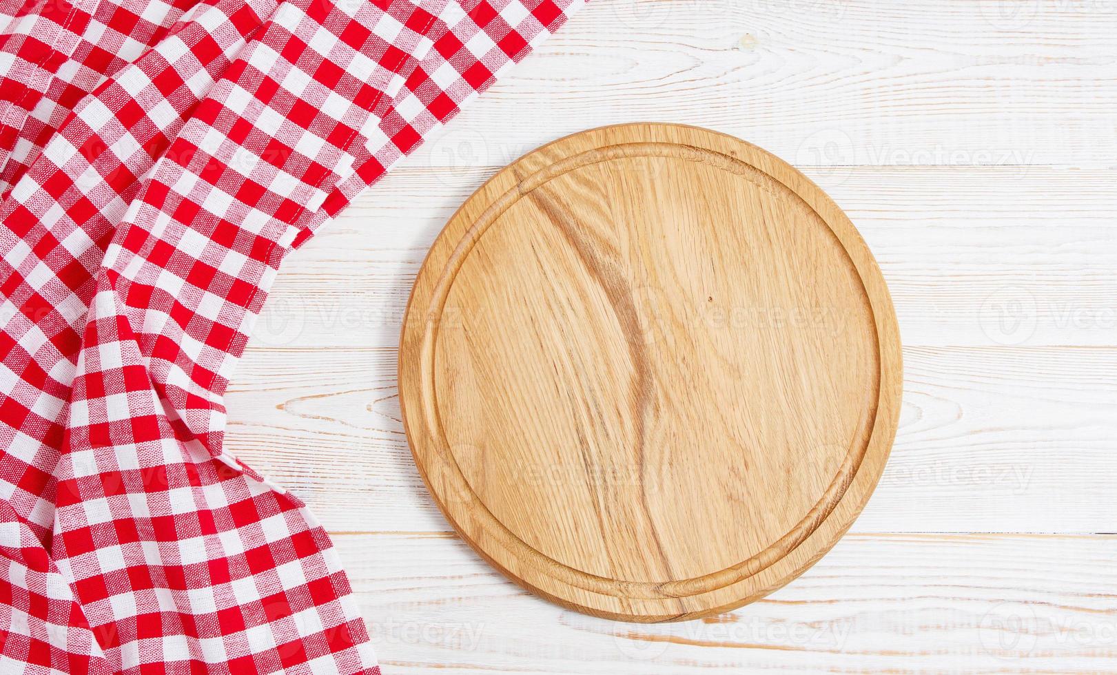 servilleta y tabla para pizza en primer plano de escritorio de madera, mantel. lienzo, paños de cocina en la vista superior de fondo de mesa de madera blanca simulacro. enfoque selectivo foto