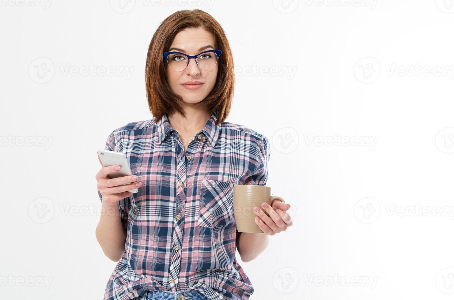 hermosa mujer con gafas sosteniendo taza de smartphone. jovencita bebiendo té y usando un gadget. concepto de rotura. vista lateral aislada sobre fondo blanco. foto