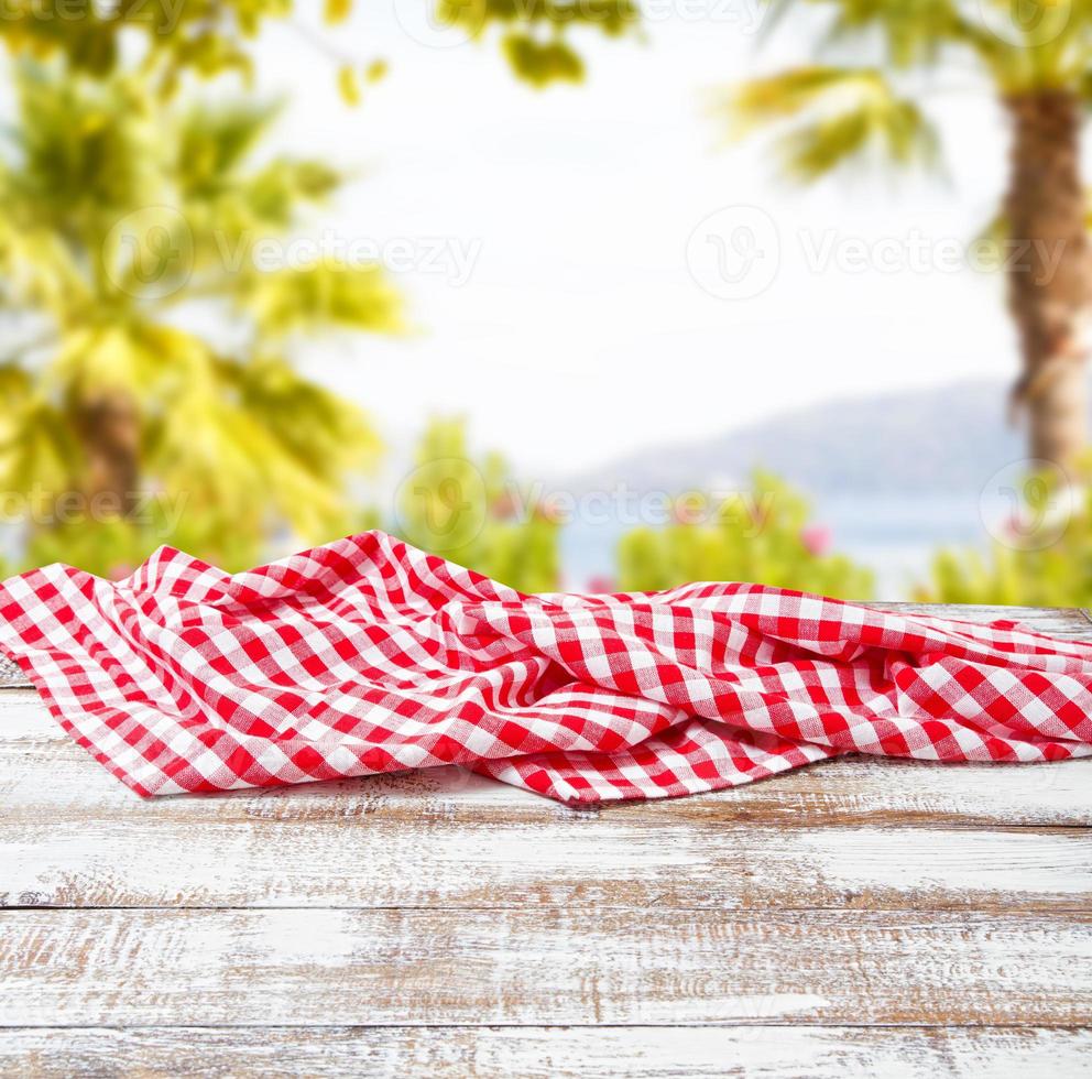 checkered tablecloth on old wooden table on blurred park background, holiday concept photo
