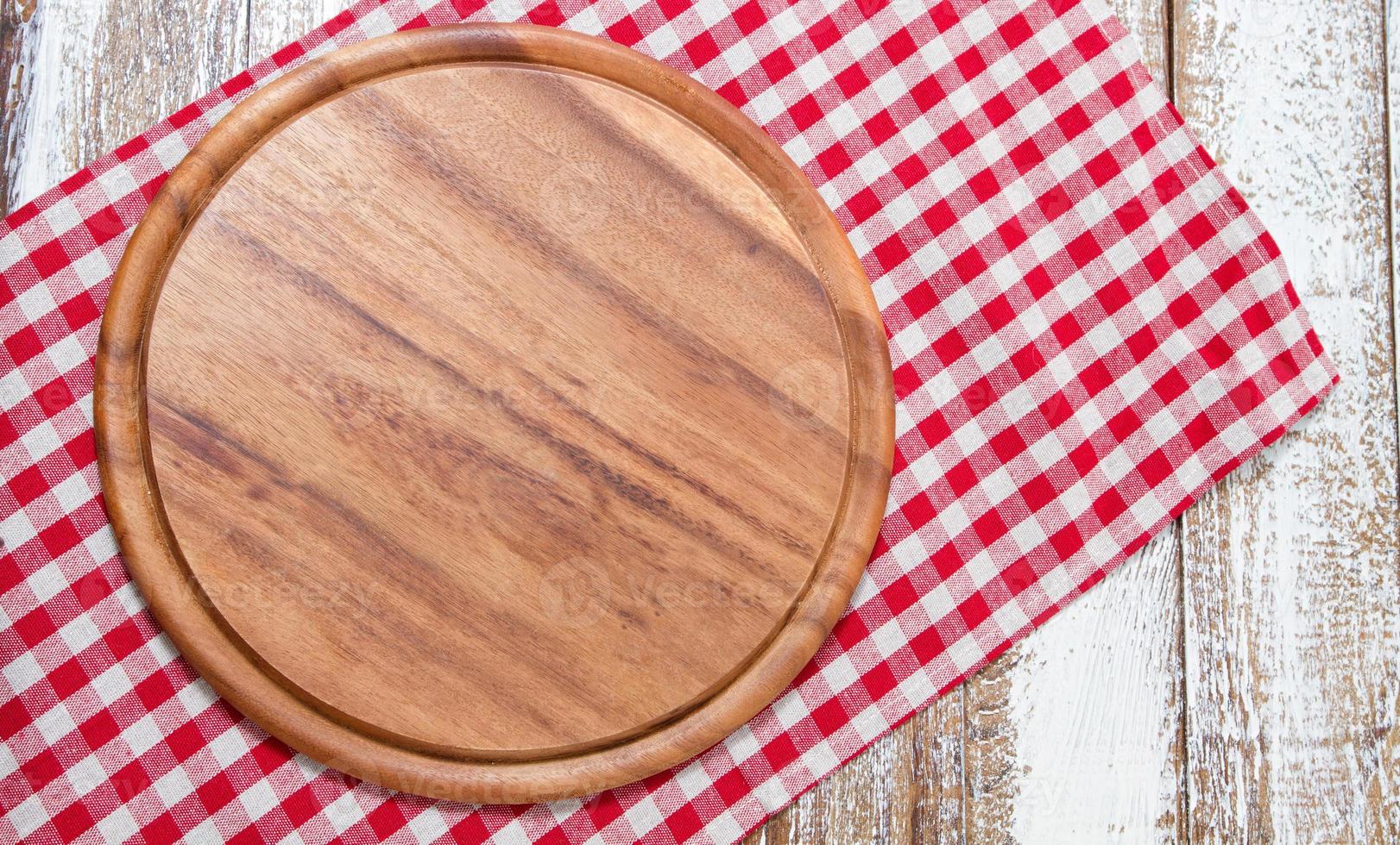 servilleta y tabla para pizza en primer plano de escritorio de madera, mantel. lienzo, paños de cocina en la vista superior de fondo de mesa de madera blanca simulacro. enfoque selectivo foto