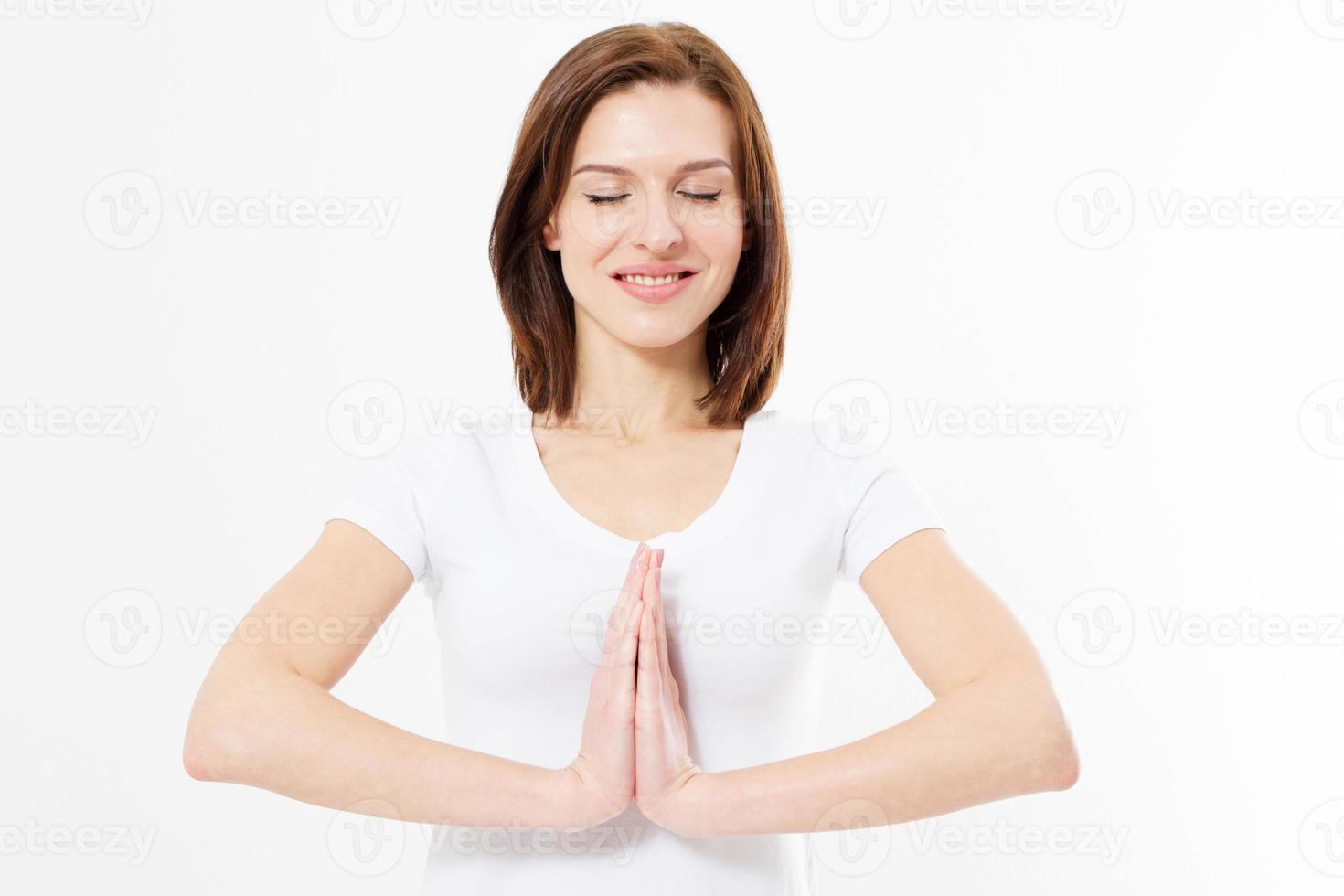 Girl in namaste gesture pose, closeup of beautiful European woman in white Tshirt isolated on white background practicing yoga and meditation, holding palms together in namaste mudra, with closed eyes photo