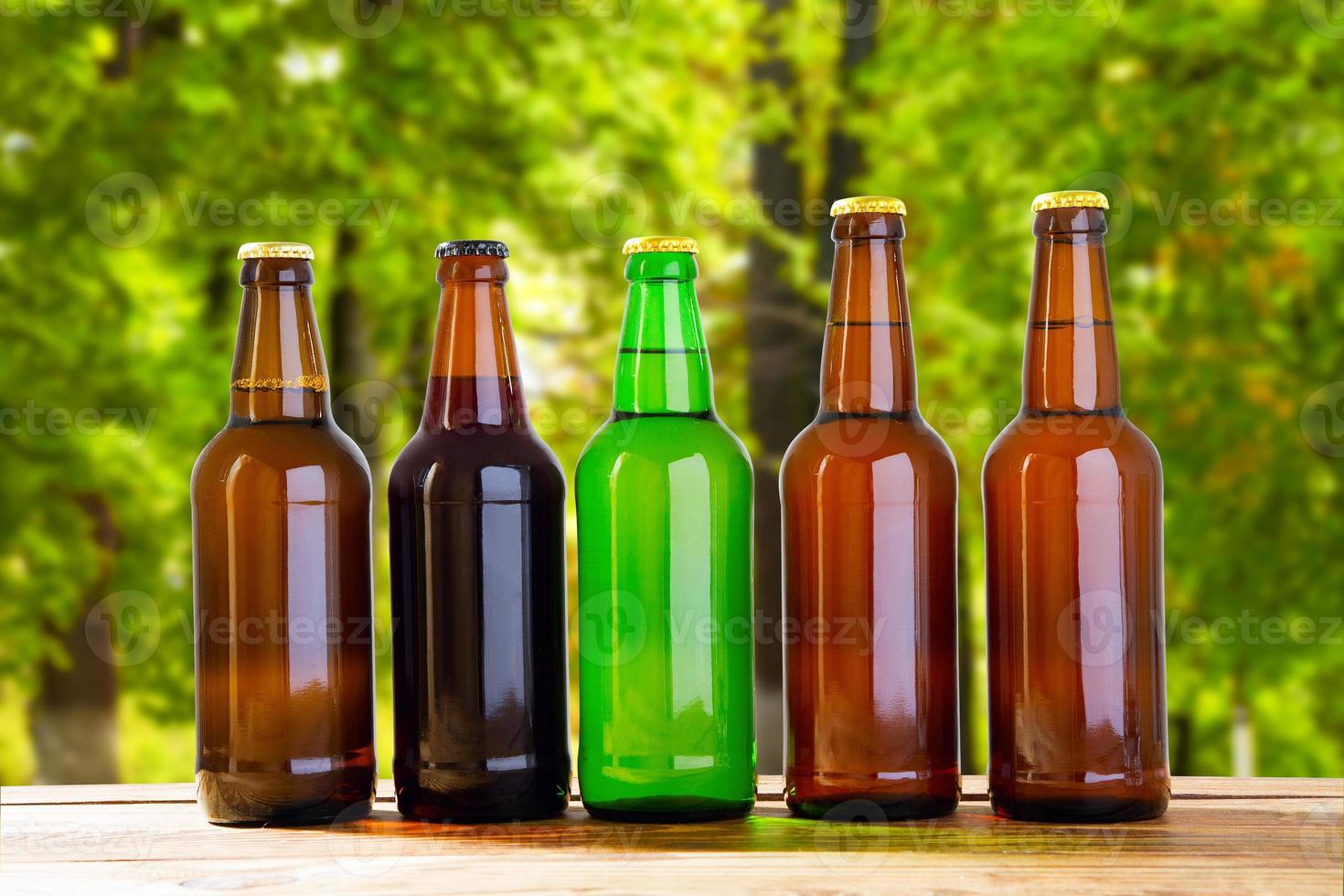 beer on table on blurred forrest background, summer drinks,coloured bottles photo