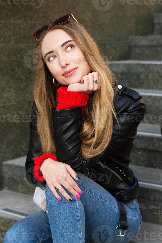 cerrar hermosa mujer joven blanca con gafas de sol, elegante suéter y chaqueta de cuero posando en la calle, hermosa mujer sexy sonrisa elegante sobre fondo urbano, mujeres blancas en la gran ciudad foto