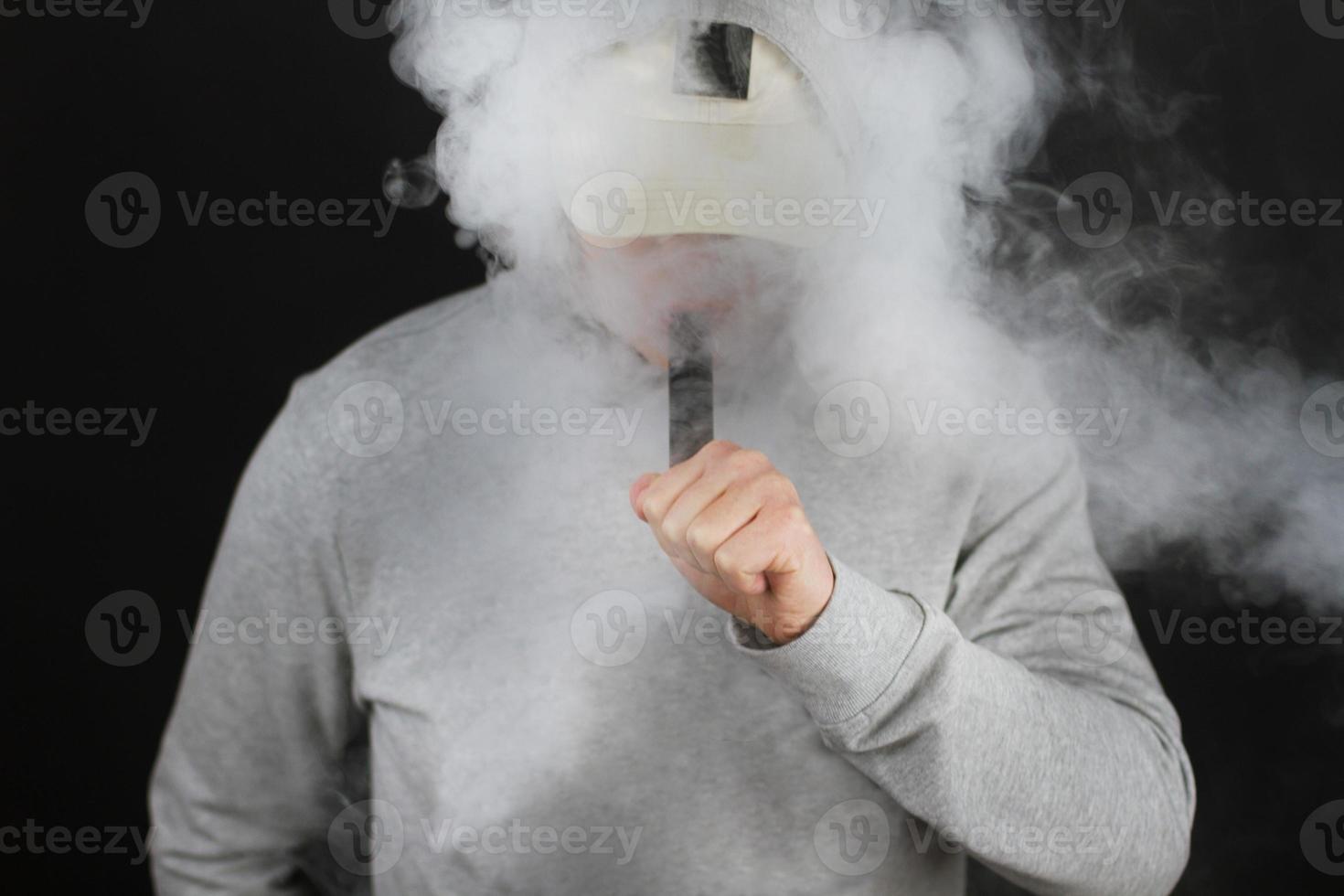 vaping man holding a mod cloud of vapor Black background isolated Selective focus photo