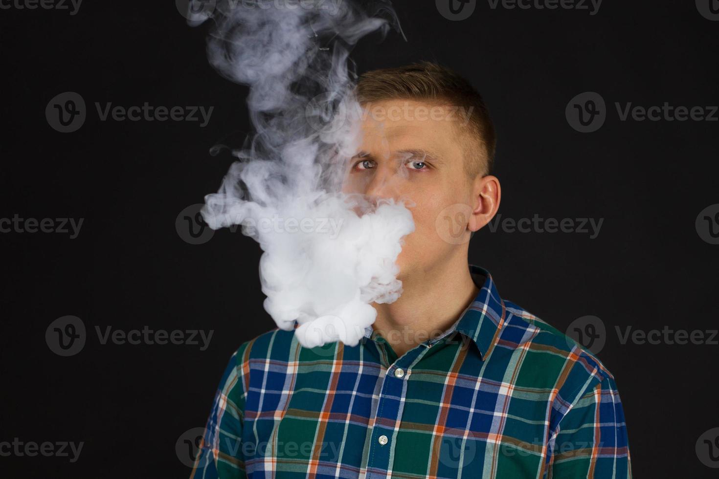 vaping man holding a mod cloud of vapor Black background isolated Selective focus photo