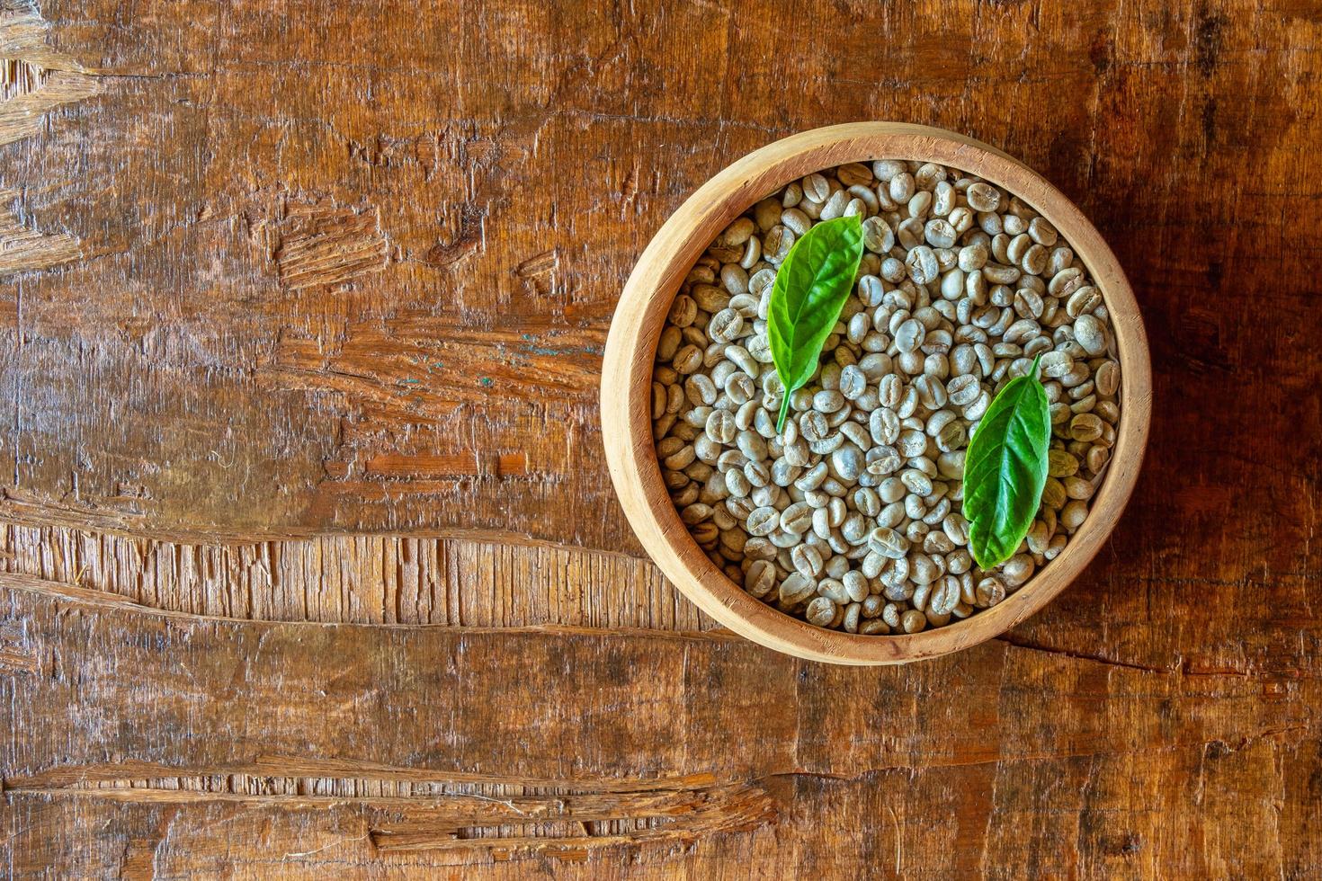 Granos de café verde sin tostar en un tazón de madera foto