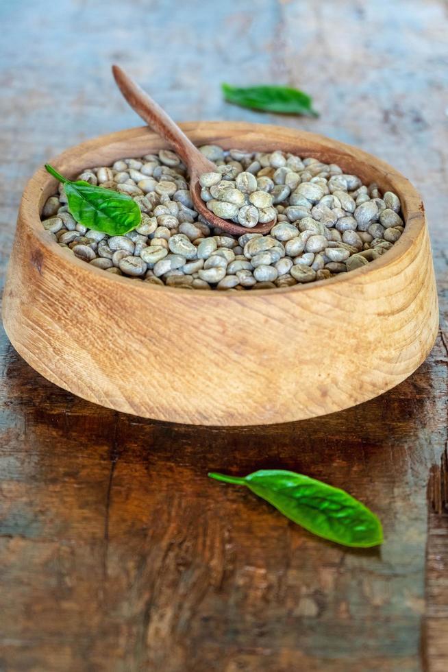 Granos de café verde sin tostar en un tazón de madera foto