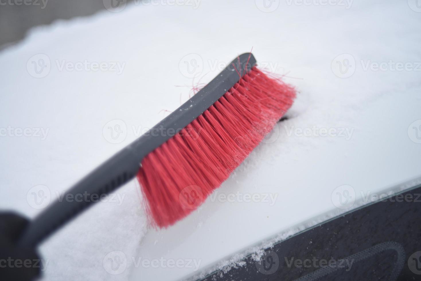 Red car brush for cleaning snow in winter in the snow photo