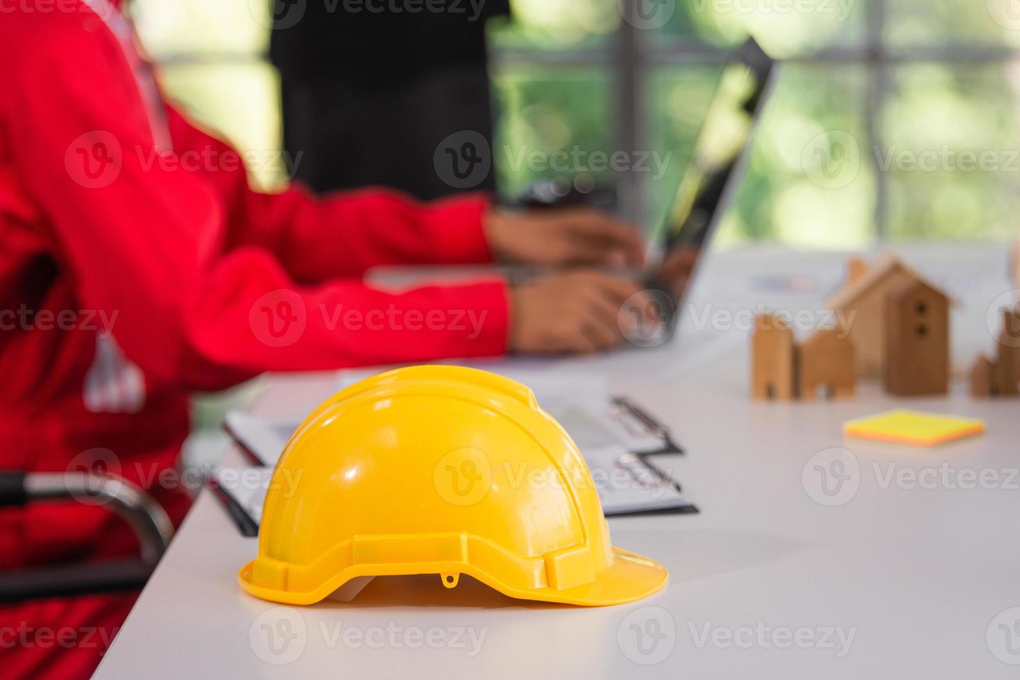 Casco amarillo en el fondo de la reunión del equipo de trabajadores de escritorio foto